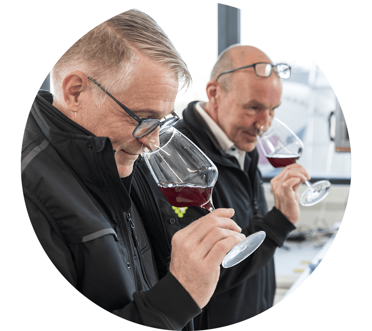 Zwei Mitarbeiter im Labor, von denen jeder an einem Glas Rotwein riecht.